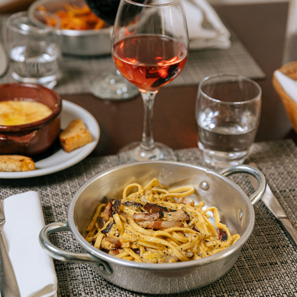 Carbonara servita nel tegame di rame, con guanciale croccante e pepe