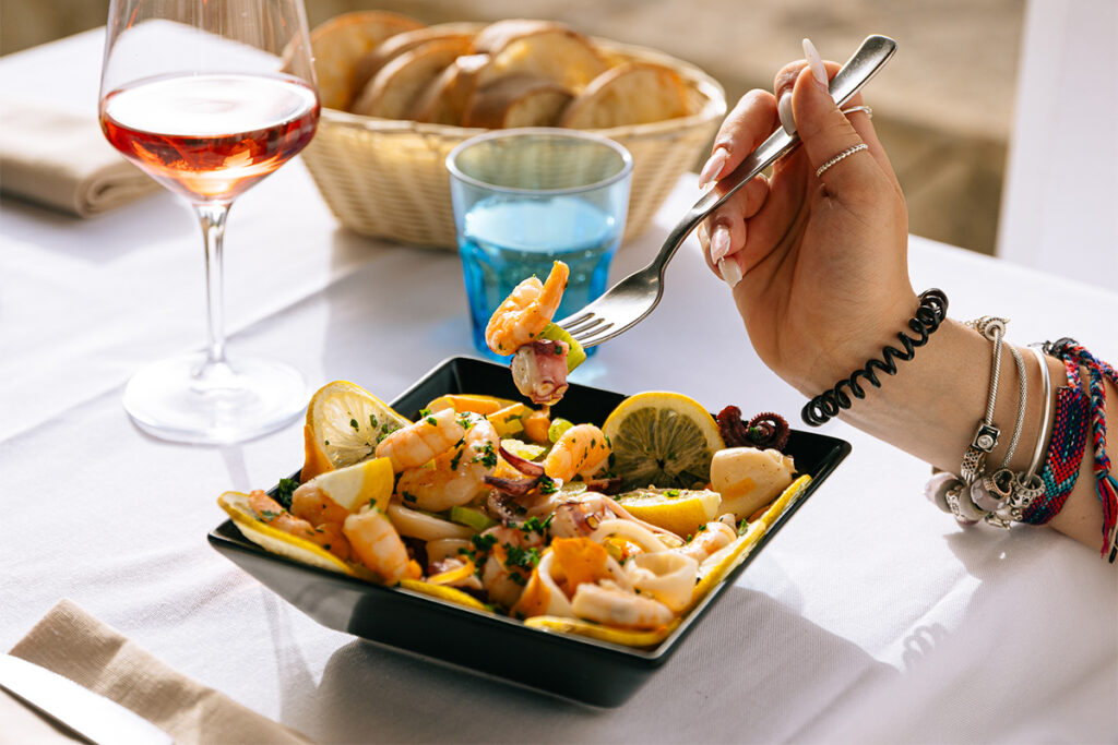 Insalata del pescatore con gamberi, calamari e polpo, servita in un piatto quadrato nero