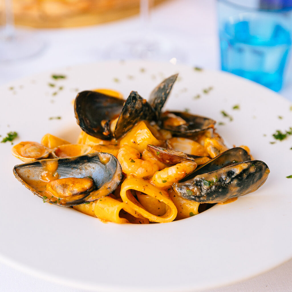 Calamarata di pasta fresca con gamberi, calamari, cozze e vongole in salsa di pomodorini