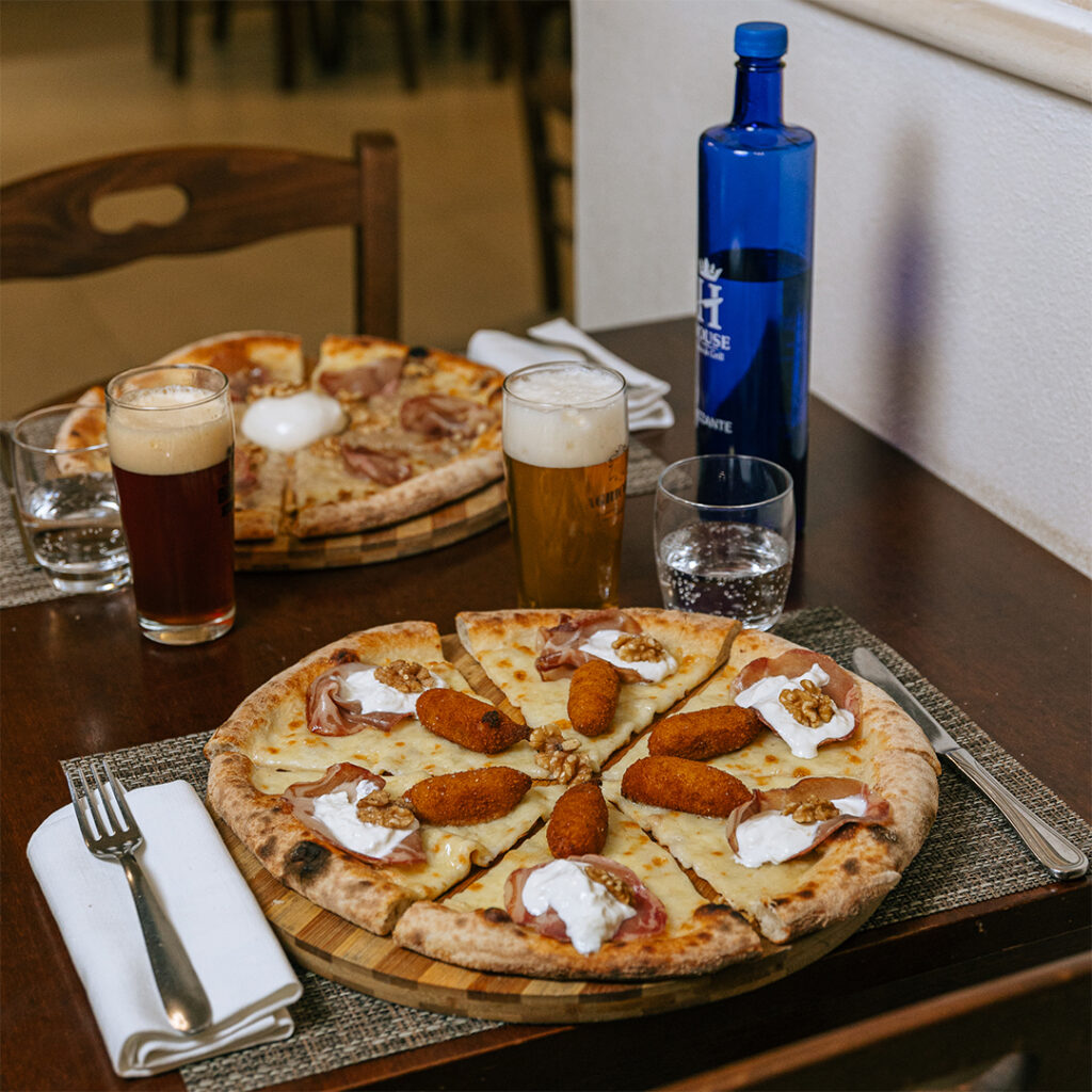 Pizza con capocollo di Martina Franca, burrata, noci e crocchette di patate, servita sul tagliere di legno