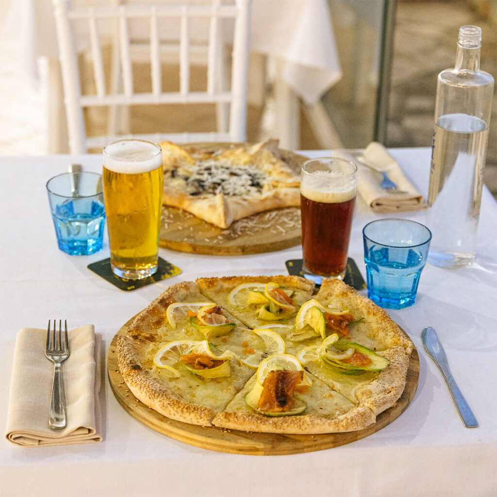 Pizza appena sfornata sul tagliere di legno, sul tavolo apparecchiato in veranda a Torre Squillace